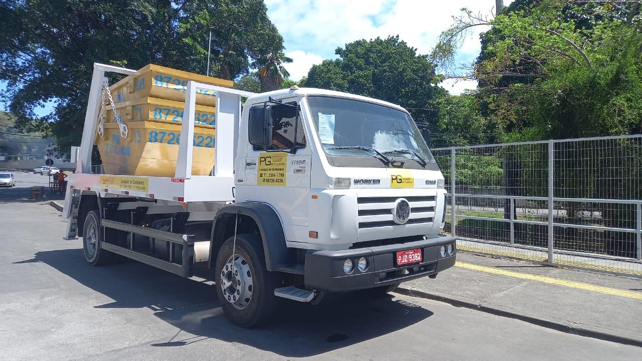 Caminhão plotado da PG Entulhos transportando caçambas